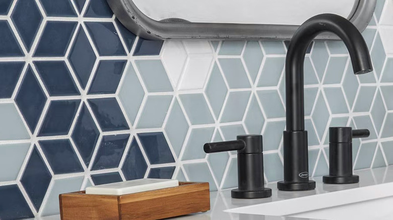 A blue mosaic backsplash is installed behind a bathroom sink