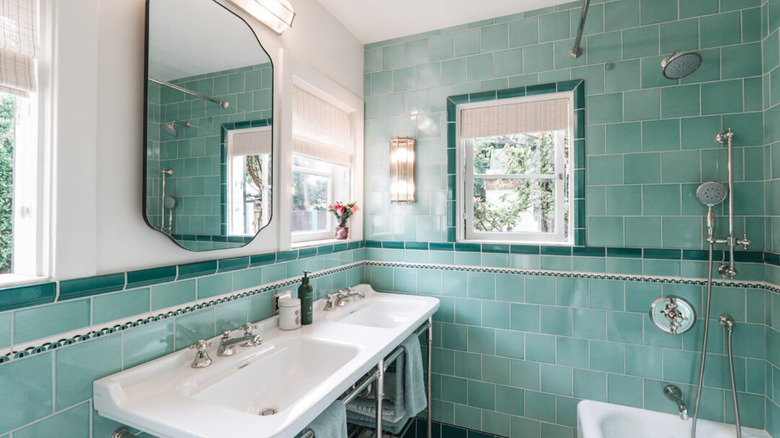 Seafoam green tiles cover the walls of a light-filled bathroom