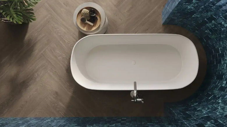 A freestanding bathtub surrounded by a curved tile wall is shown in a overhead shot
