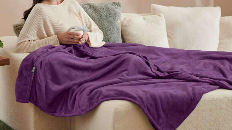 Person lounging on couch with purple fleece blanket