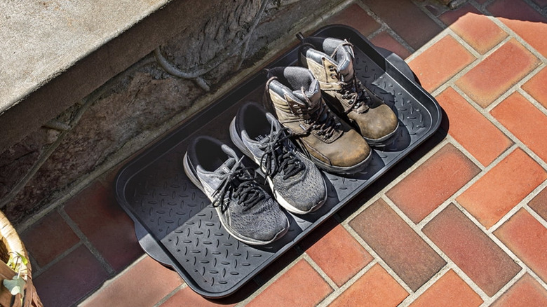 Boot tray on brick floor with two pairs of shoes on top