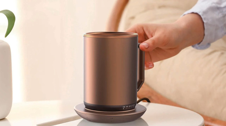 Hand reaching for heated copper colored mug