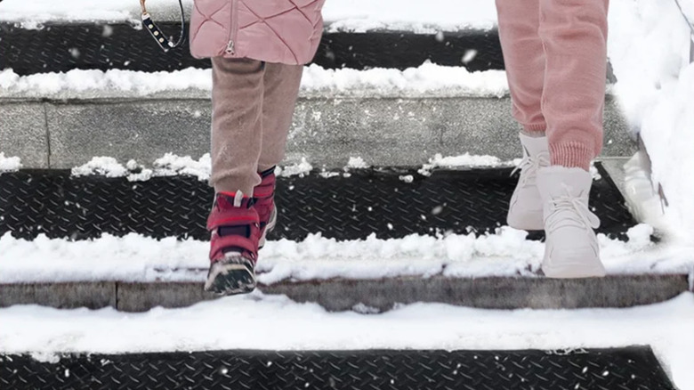 Close-up of booted feet walking over snow melting mats