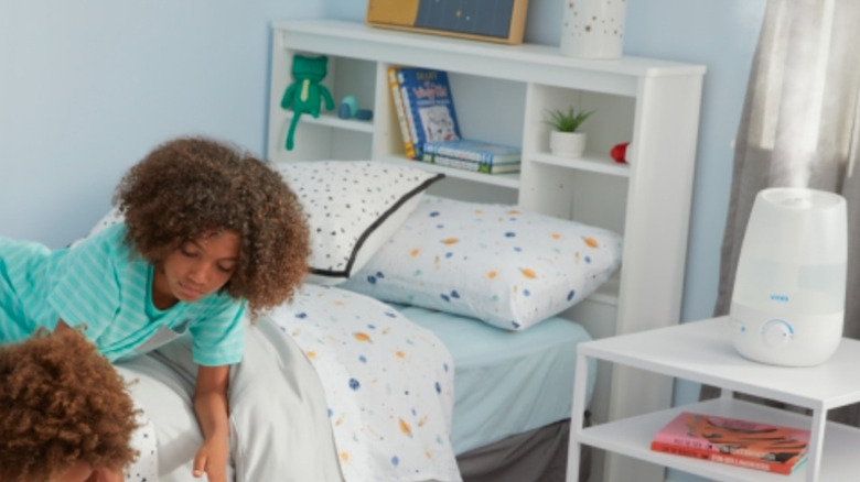 Vicks humidifier in kids room with curly-haired child on bed