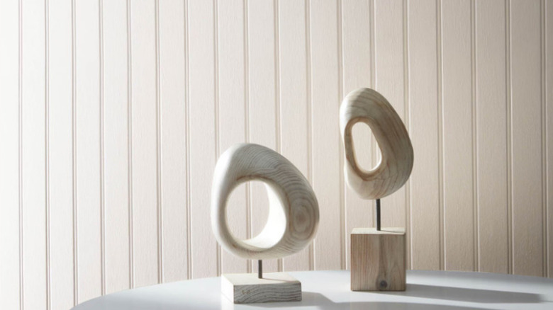 Wooden circular sculpures on a white table against a wall painted A la Mode.