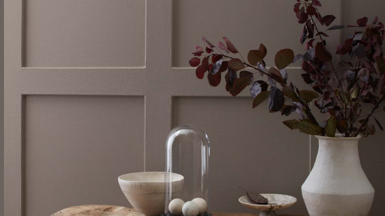 A plant in a vase on a table with a Coachman's Cape-painted wall in the background.
