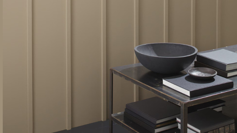 A textured wall painted Nordic Gray and a dark wood side table with books