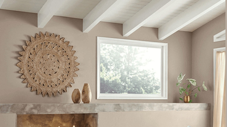 A marble mantle against a Perfect Greige wall with plants and window.