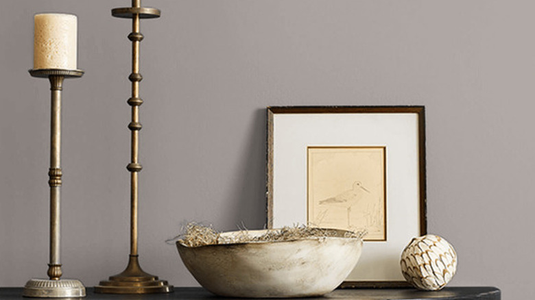 A bowl and picture frame leaning against a soft gray wall.