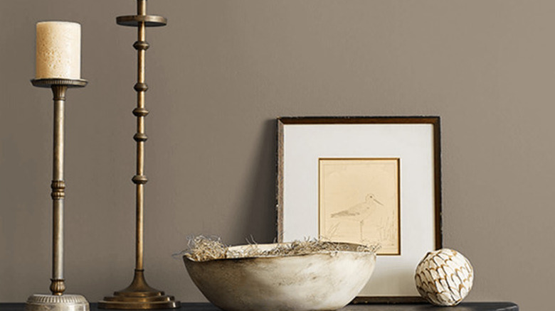 Candlesticks and a picture frame against a wall painted Warm Stone