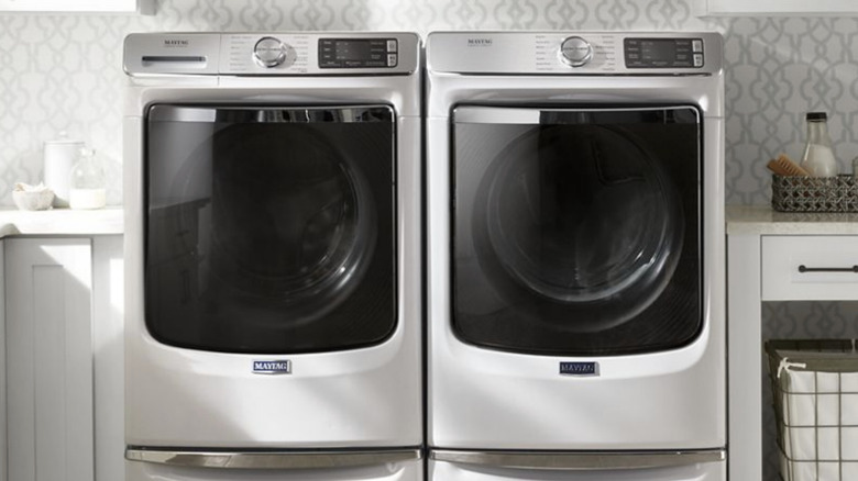 Silver-colored front-loading washer and dryer in a spacious laundry room