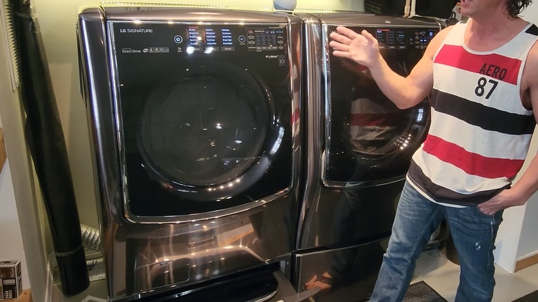 Man standing beside a LG dryer sitting near a LG Signature washer