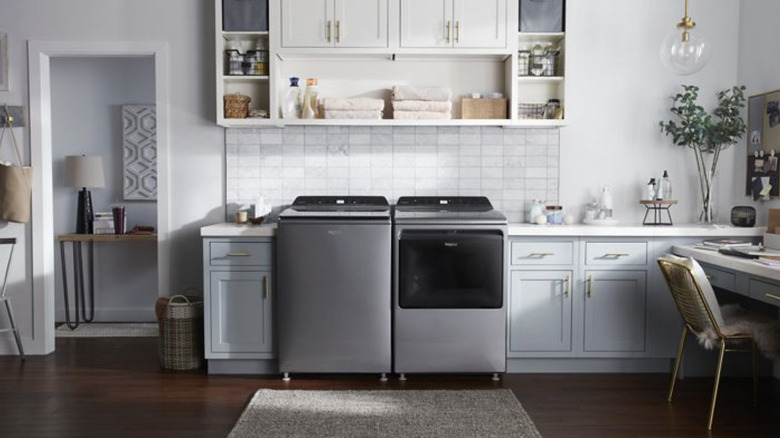 Silver colored top loading washer and dryer in a laundry room