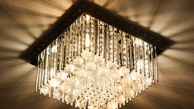 A crystal light fixture casts textural shadows on a ceiling