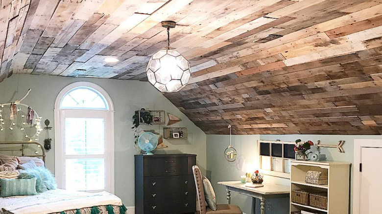 A hexagonal ceiling fixture hangs from a wood pallet covered ceiling