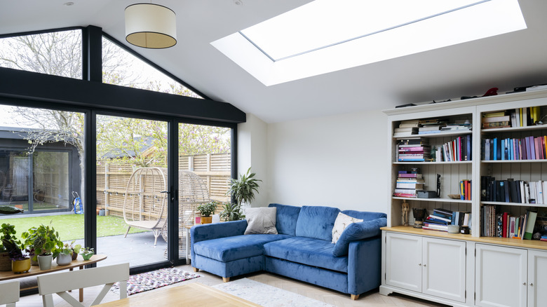 A large skylight and glass doors flood a living room with natural light