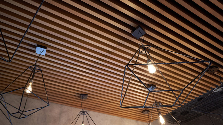 Geometric wire pendant lights hang from a wooden slat ceiling