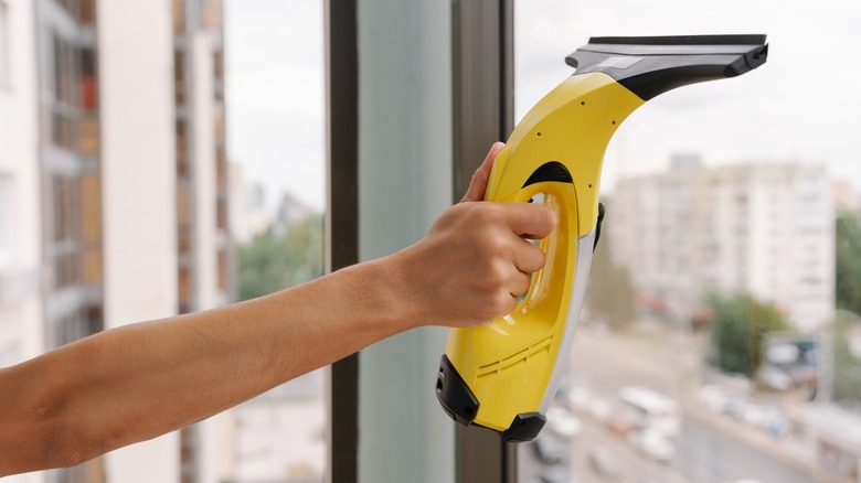 A person using a handheld cleaner on windows