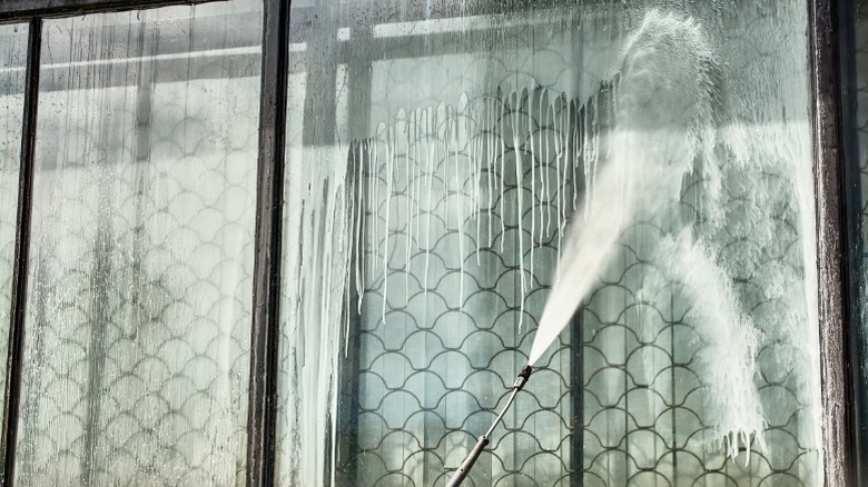 A pressure washer being used to clean large windows