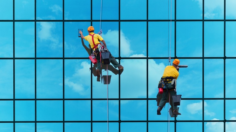 Workers on a harness cleaning corporate building windows