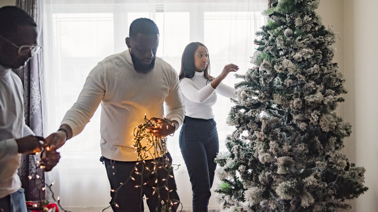 Family setting up a Christmas tree indoors