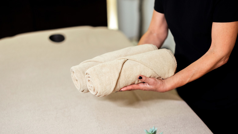 Woman holding advanced spa rolled towels.