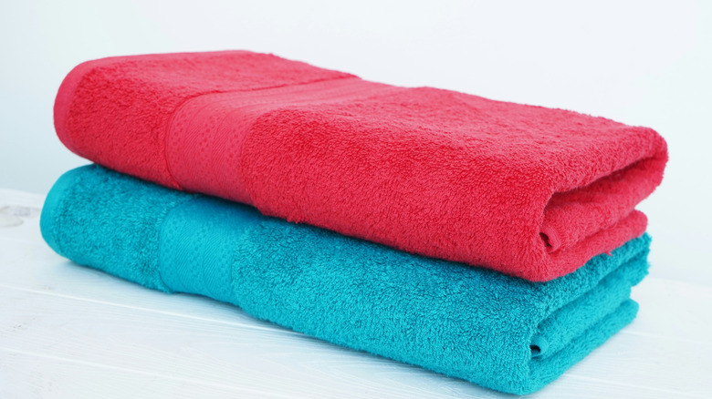 Two tri-folded towels on white surface.