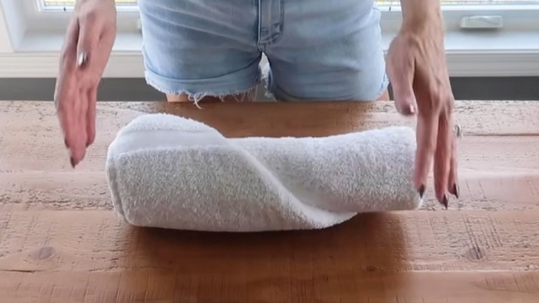Rolled white towel on table.