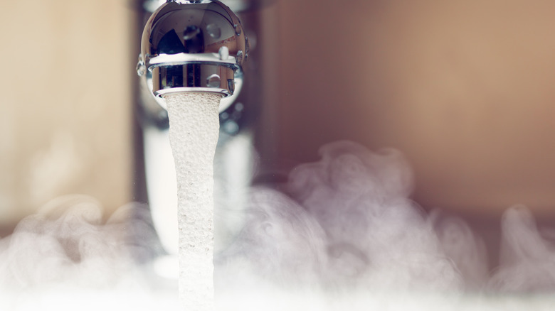 Hot water pouring out of a tap creating steam