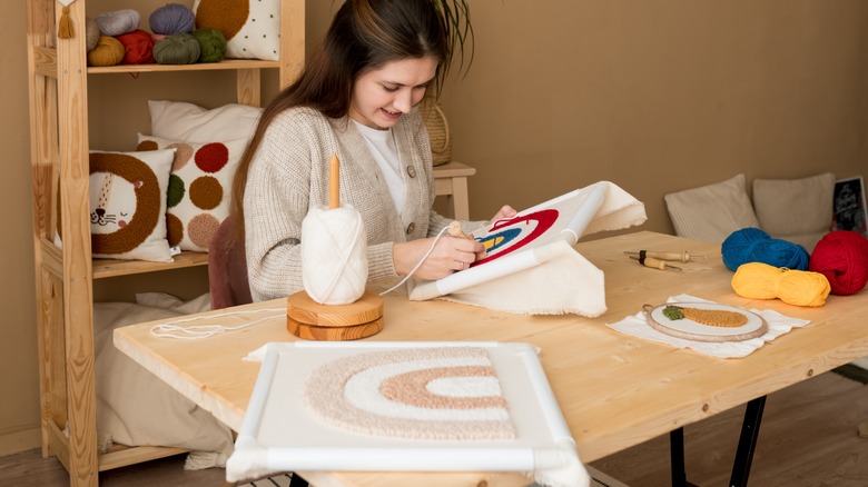 woman embroidering rainbow wall art