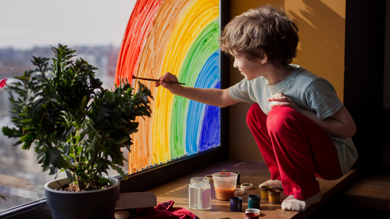 Little boy painting window glass