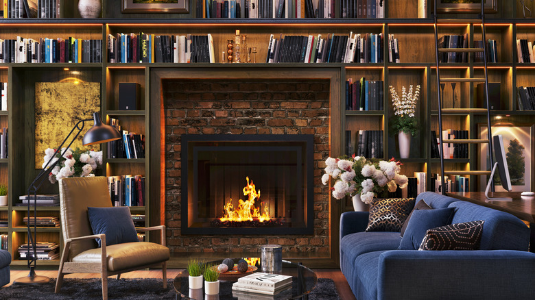 Library with built-in bookshelves, brick fireplace, leather chair, and chenille sofa