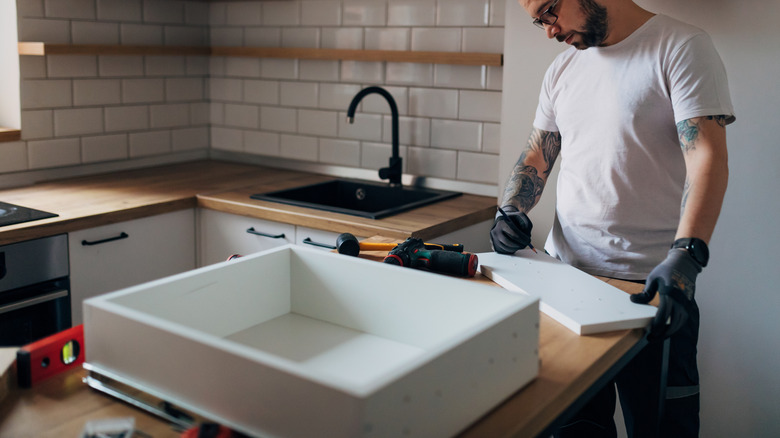 A craftsman installing cabinetry in a kitchen