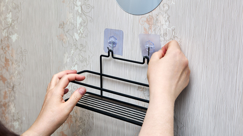 Close up of person hanging up metal basket on wall