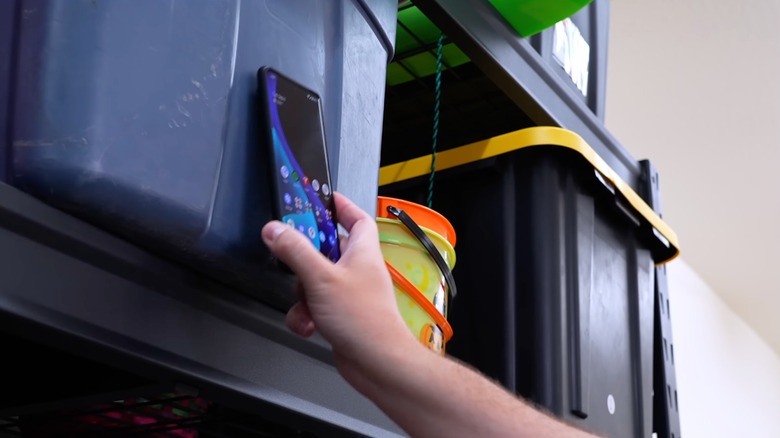 Person tapping a phone on a storage bin