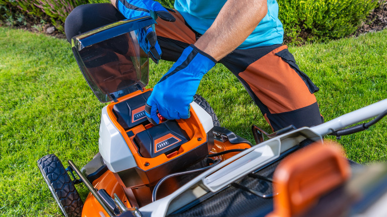 Person removing batteries on electric lawn mower