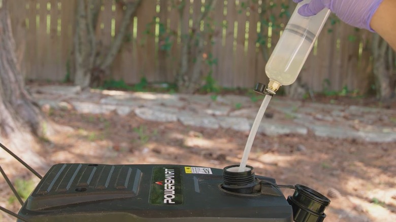 Person using a gas siphon to remove gas from mower