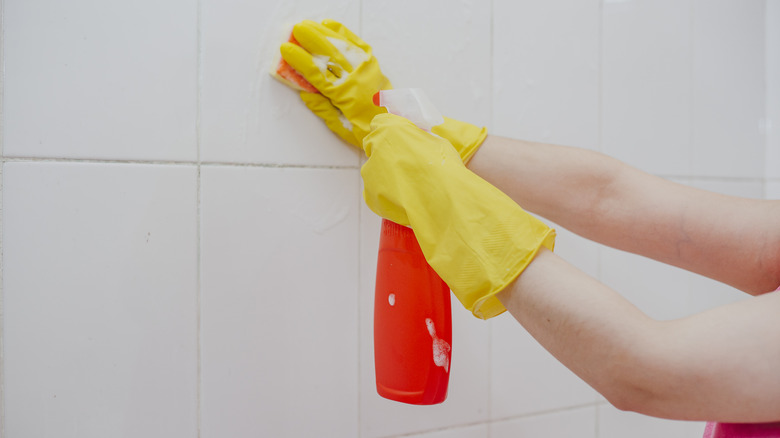 person cleaning white tile wall