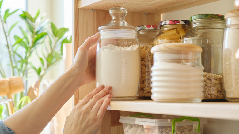 A person organizing pantry staples on a shelf