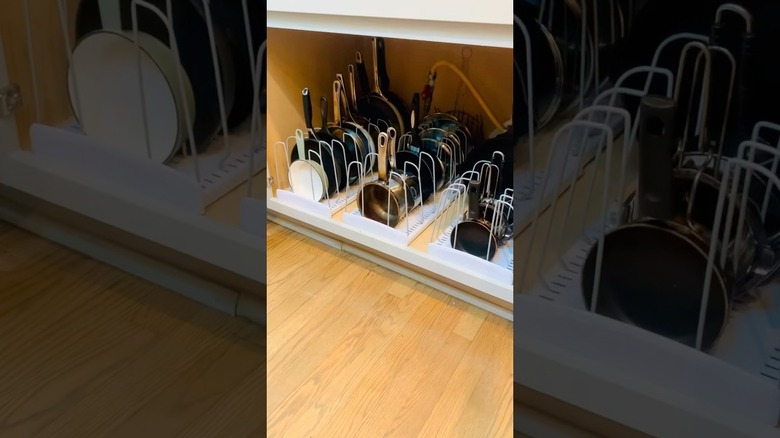 Close up of measuring cups stored in pan lids under cabinet