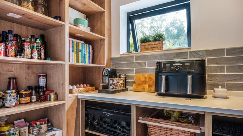 A pantry room with an air fryer and coffee maker on the counter