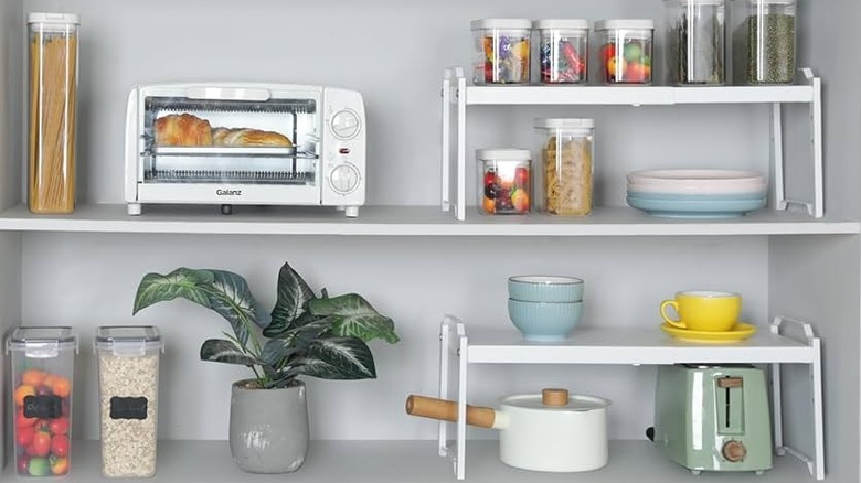 White shelf risers in a kitchen cupboard