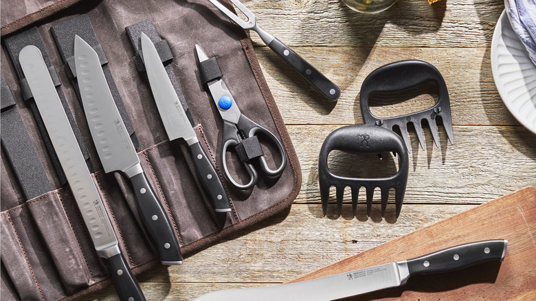 Steel and plastic barbecue tools unrolled from leather organizer on wood table