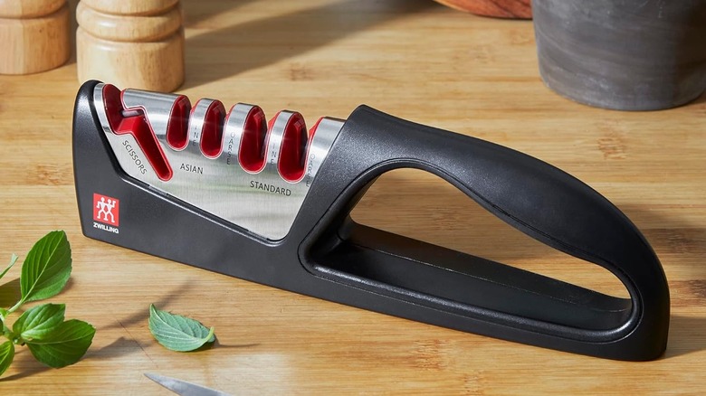 Brand new knife sharpener with several sharpening slots on wooden counter