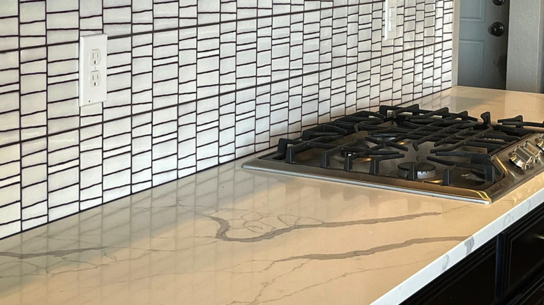 A marble countertop fitted with a cooking range and a white zellige tile backsplash.