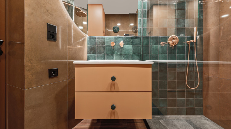 A bathroom with a blue zellige tile backsplash and terracotta walls and floors.