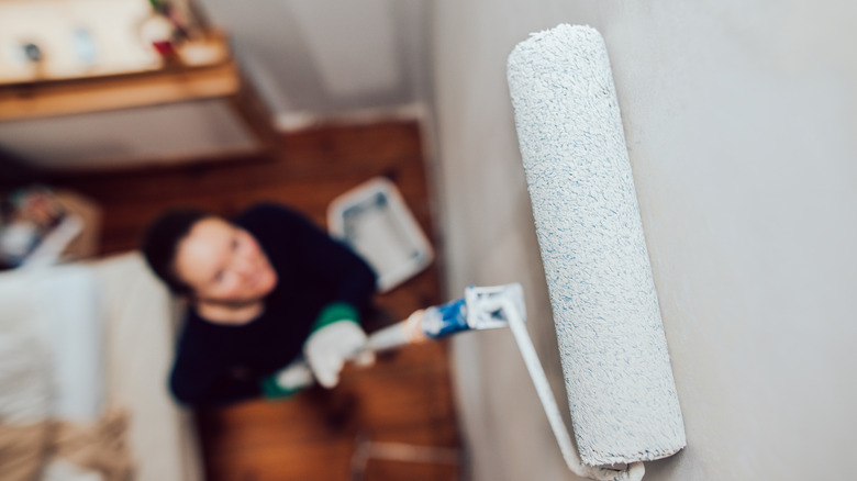 Woman painting wall with paint roller