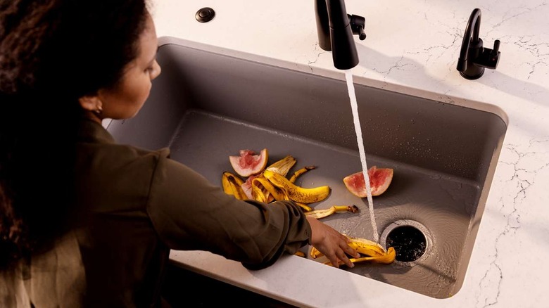 A person using an InSinkErator garbage disposal system to dispose of fruit peels