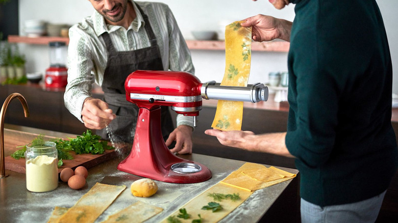 Two people making pasta with KitchenAid's stand mixer and pasta roller attachment