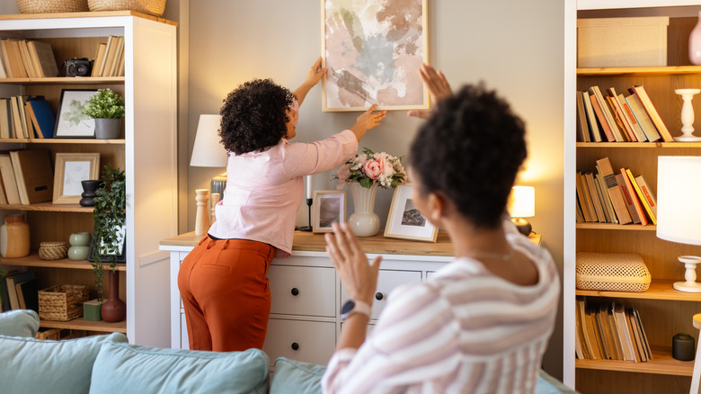 Two women decorating a home with photo frames